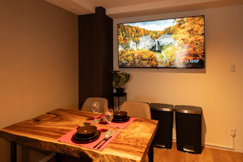 民泊撮影事例:一枚板のテーブルと壁掛けテレビのある部屋